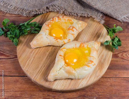 Adjarian khachapuri on the wooden serving board on rustic table photo