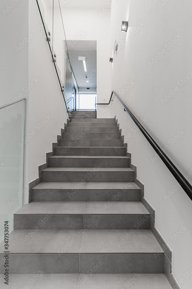 Clean white stairway staircase with glass railing in corridor in office building Clean white stairway staircase with glass railing in corridor in office building