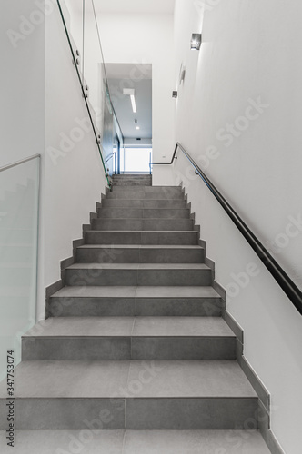 Clean white stairway staircase with glass railing in corridor in office building 