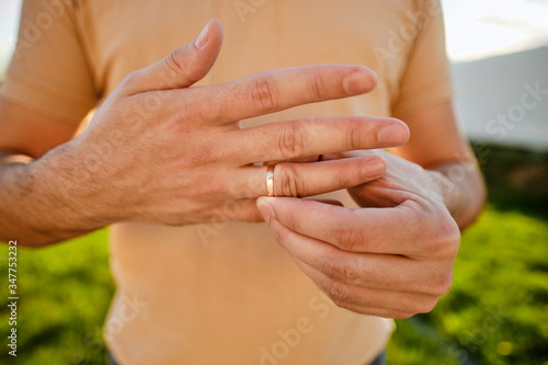 Concept of family quarrel, divorce or betrayal. Man removes a gold wedding ring from his finger.