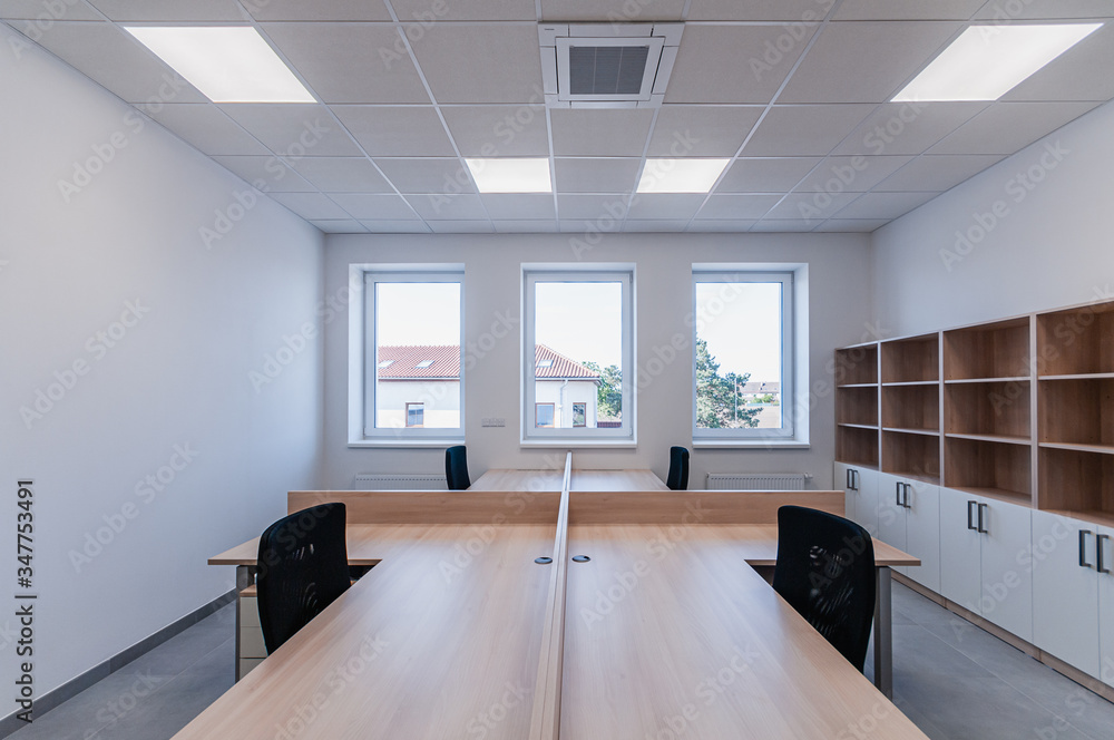 Interior of small new empty office space with desks and chairs Interior of small new empty office space with desks and chairs