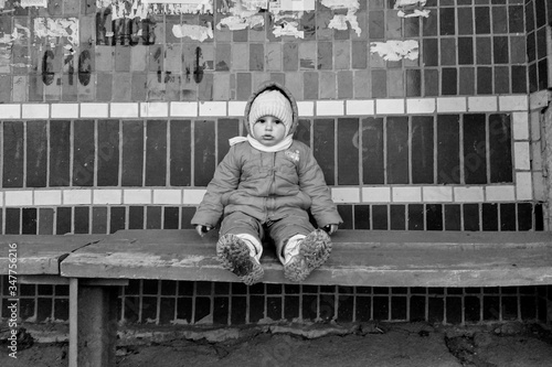Little girl sit on bench on bus stop