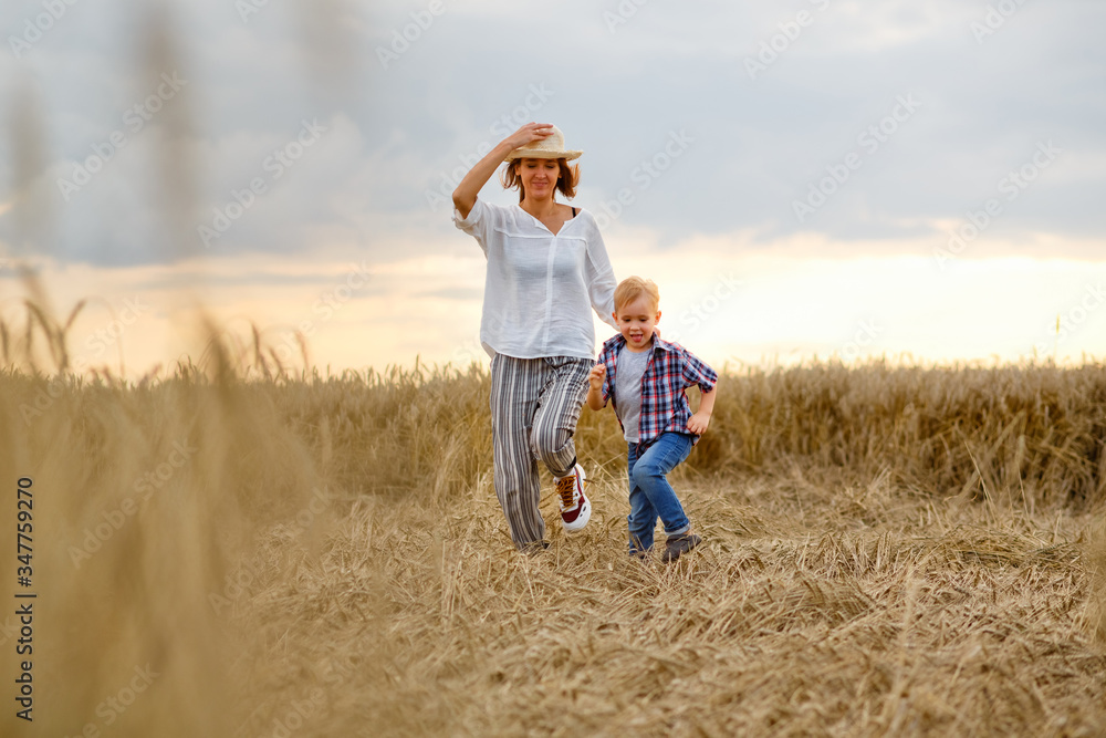 Happy mother and son are running through a wheat field in summer Happy mother and son are running through a wheat field in summer