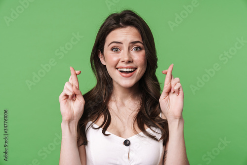 Image of pleased young woman posing with fingers crossed for good luck