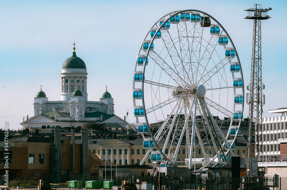 A summer cityscape from downtown with Helsinki Cathedral and city ferris wheel.
