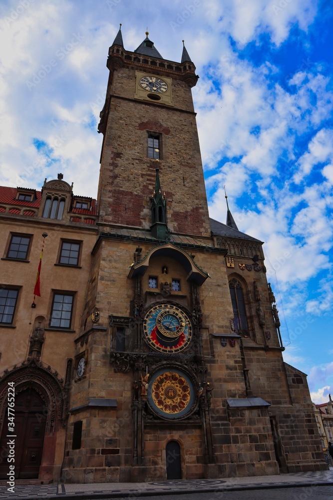 Prague Astronomical Clock in empty Prague during quarantine with beautiful clouds on blue sky.