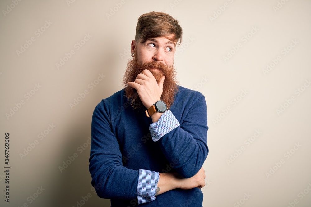 Handsome Irish redhead business man with beard standing over isolated background with hand on chin thinking about question, pensive expression. Smiling with thoughtful face. Doubt concept. Handsome Irish redhead business man with beard standing over isolated background with hand on chin thinking about question, pensive expression. Smiling with thoughtful face. Doubt concept.