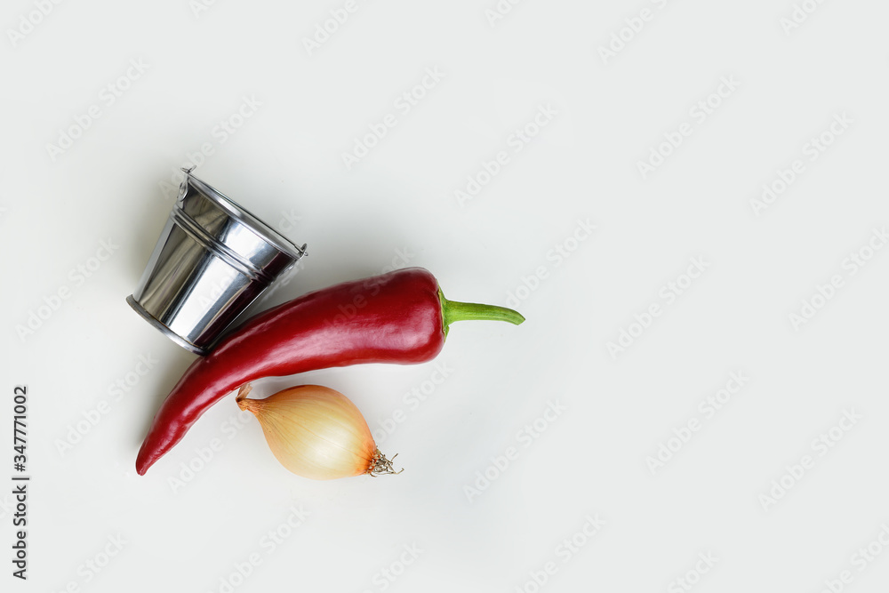 on a white background, a bucket,red pepper and onion