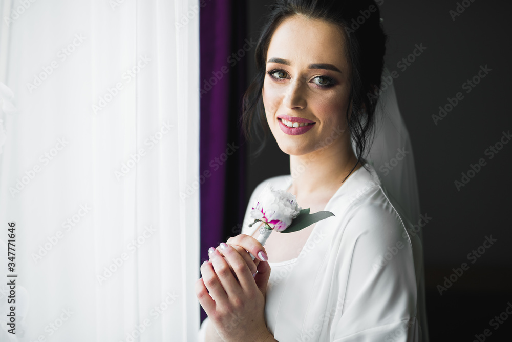 Gorgeous bride in robe posing and preparing for the wedding ceremony face in a room Gorgeous bride in robe posing and preparing for the wedding ceremony face in a room