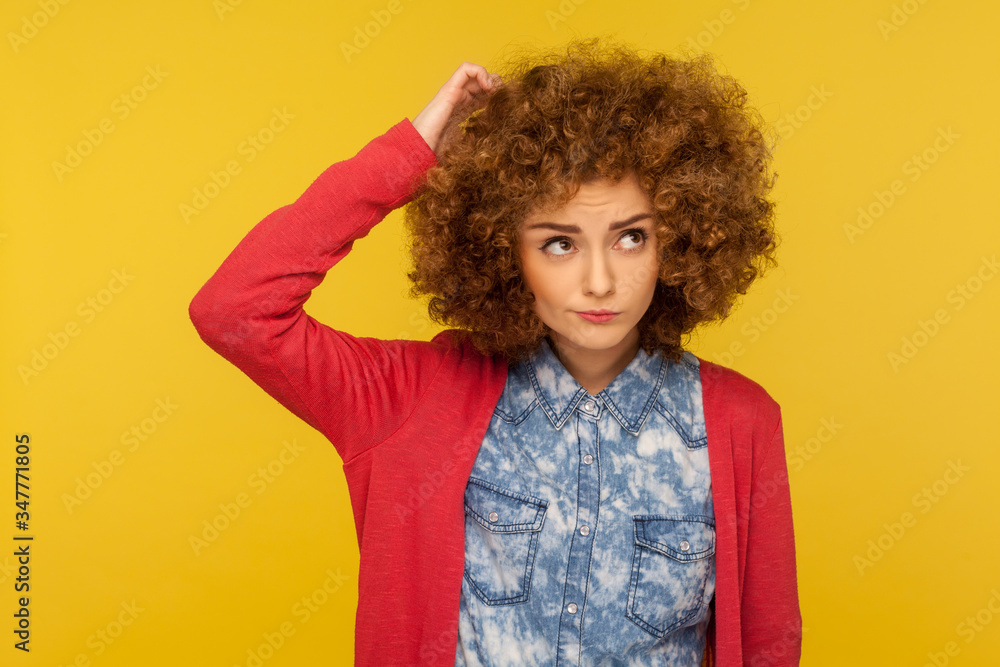 Deep in thoughts. Portrait of pensive confused woman with curly hair in casual outfit scratching head, wondering and having doubts, pondering idea. indoor studio shot isolated on yellow background Deep in thoughts. Portrait of pensive confused woman with curly hair in casual outfit scratching head, wondering and having doubts, pondering idea. indoor studio shot isolated on yellow background