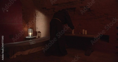 Monk lighting candles in front of the altar in the dark room.