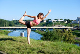 Pretty slim woman practicing yoga outdoors. City on background. Concept love morning.