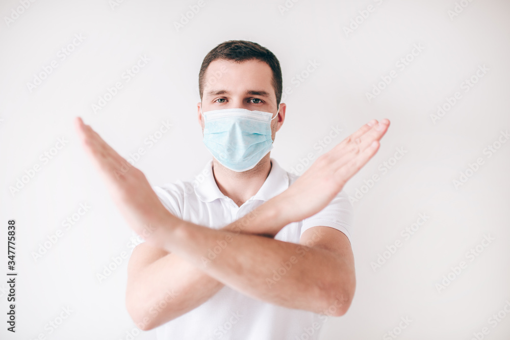 Young sick man isolated over white background. Showing stop sign with hands. Forbidden moment. Guy wear medical mask for facial protection. Young sick man isolated over white background. Showing stop sign with hands. Forbidden moment. Guy wear medical mask for facial protection.