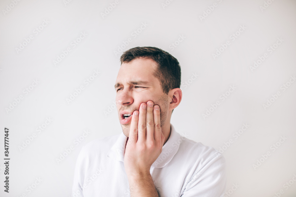 Young man isolated over white background. Guy suffer from tooth pain and ache. Need oral care and treatment. Hold hand on cheek. Young man isolated over white background. Guy suffer from tooth pain and ache. Need oral care and treatment. Hold hand on cheek.