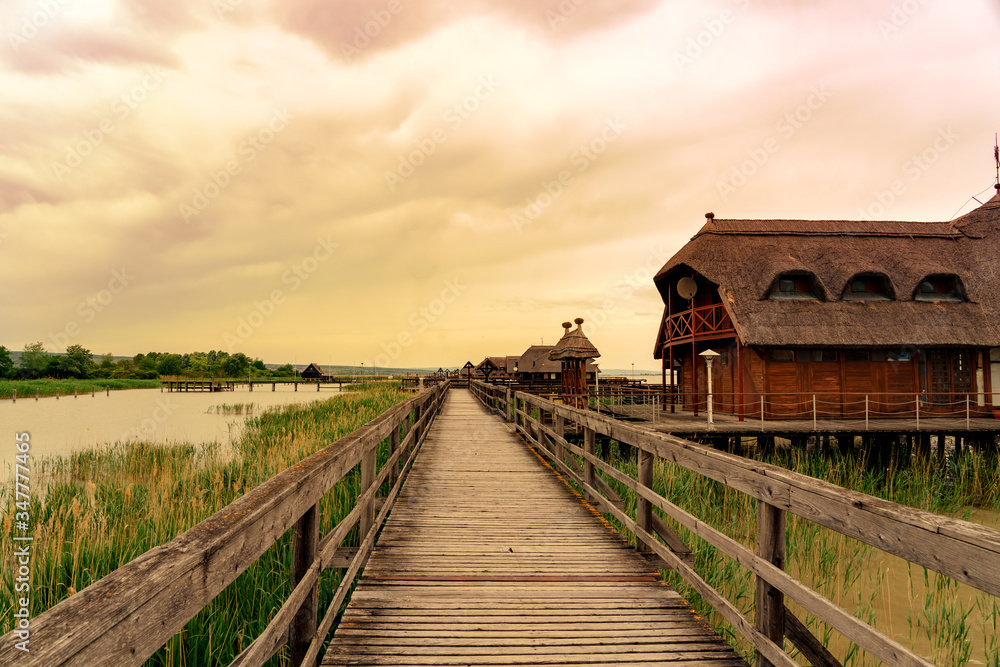 peaceful nature at the Lake Fertő in Hungary with wooden pier bungalows cabins on the lake and straw in the water at sunset