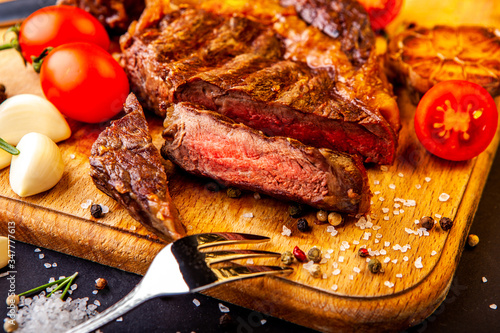 Fresh juicy ribeye steak with a set of spices on a cutting board