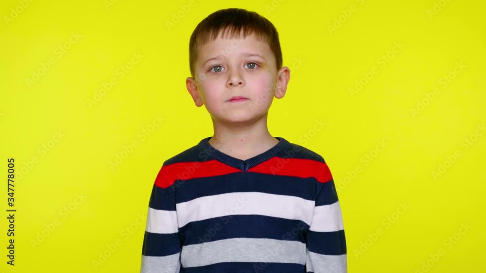 Serious little child boy in a colorful sweater says yes on a yellow background with copy space. Place for text or product. 4K slowmotion footage Serious little child boy in a colorful sweater says yes on a yellow background with copy space. Place for text or product. 4K slowmotion footage