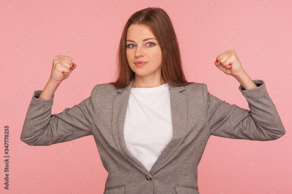 Portrait of confident ambitious independent young woman in business suit raising hands proudly showing biceps, feeling power, female strength, rights and feminism. indoor studio shot, isolated Portrait of confident ambitious independent young woman in business suit raising hands proudly showing biceps, feeling power, female strength, rights and feminism. indoor studio shot, isolated