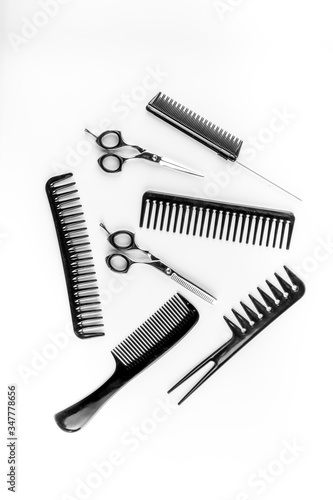Combs, hairbrush, scissors - hairdresser eqiupment - on white table top-down