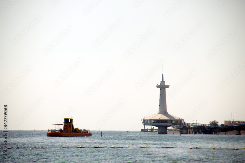 Fototapeta premium Photo with marine landscape in Eilat, Istael. View with lighthouse and yellow boat.