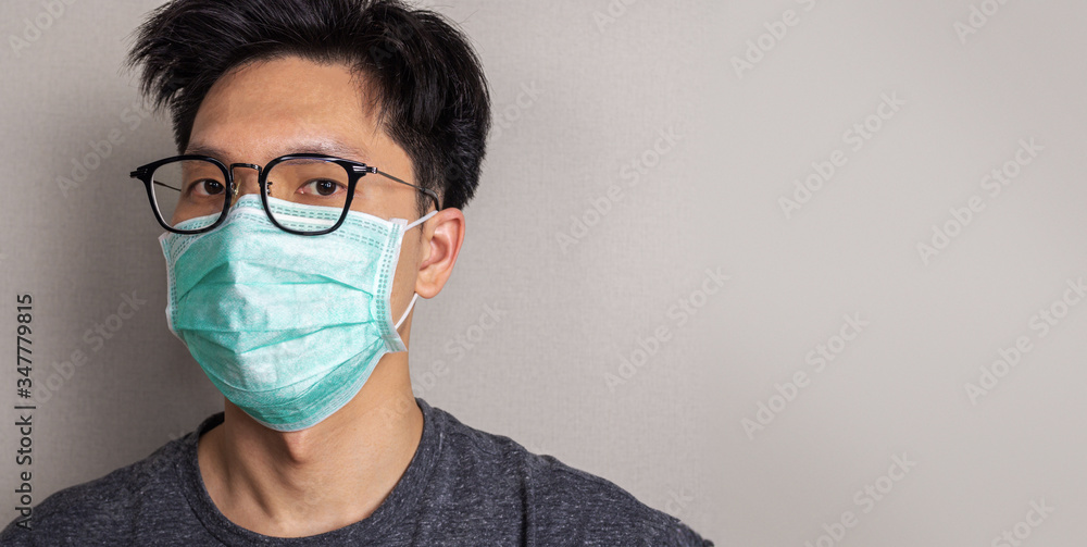 Asian man wearing white face mask and eye glasses close up