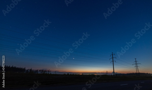 The sunset and the starry sky above the power lines.