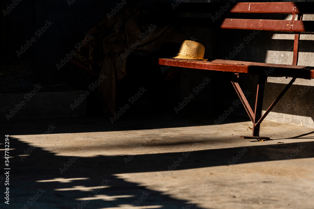Fototapeta A straw hat left on a red bench before entering Sunday morning church sermon in a village.