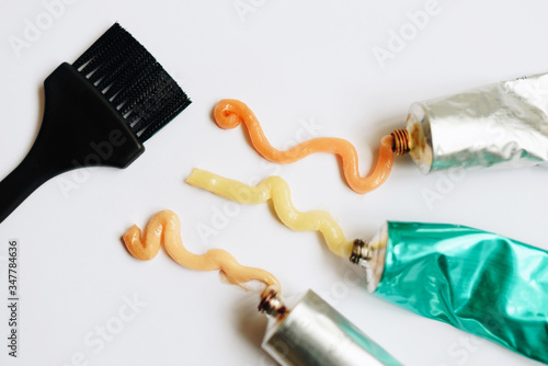 Squeezed out tubes of hair dye and brush on a white background