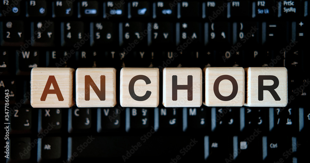 Anchor - concept text on wooden cubes on background black keyboard Anchor - concept text on wooden cubes on background black keyboard