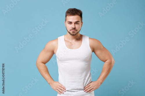 Canvas Print Handsome young bearded guy 20s in white singlet posing isolated on pastel blue wall background studio
