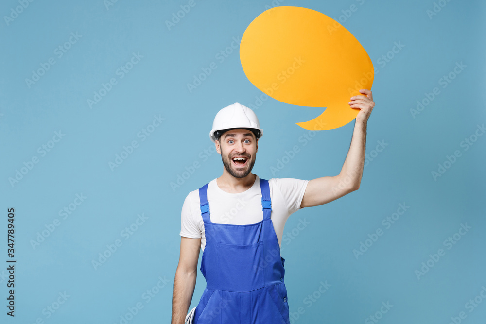 Excited man in coveralls protective helmet hardhat hold empty blank Say cloud speech bubble isolated on blue background. Instruments accessories for renovation apartment room. Repair home concept. Excited man in coveralls protective helmet hardhat hold empty blank Say cloud speech bubble isolated on blue background. Instruments accessories for renovation apartment room. Repair home concept.