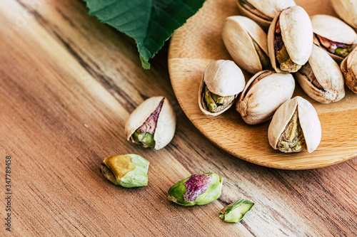 Délicieuses pistaches dans un bol sur la table en bois © PicsArt