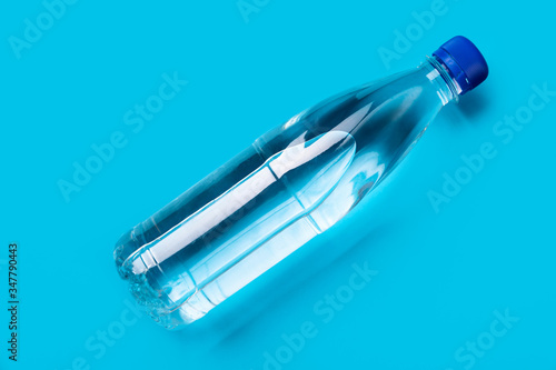 plastic bottle of water with a blue cap on a blue background shot from above