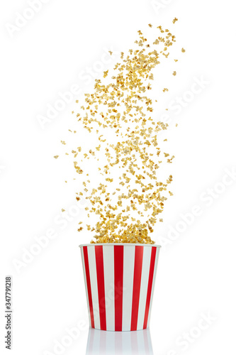 Flying popcorn from red and white paper striped bucket isolated over the white background. Cinema style popcorn