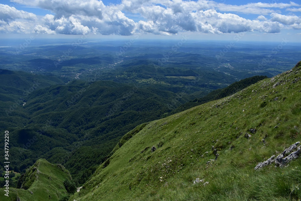 horizon seen from above in top of the mountain on summer day with white clouds and green grass