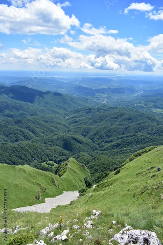 horizon seen from above in top of the mountain on summer day with white clouds and green grass