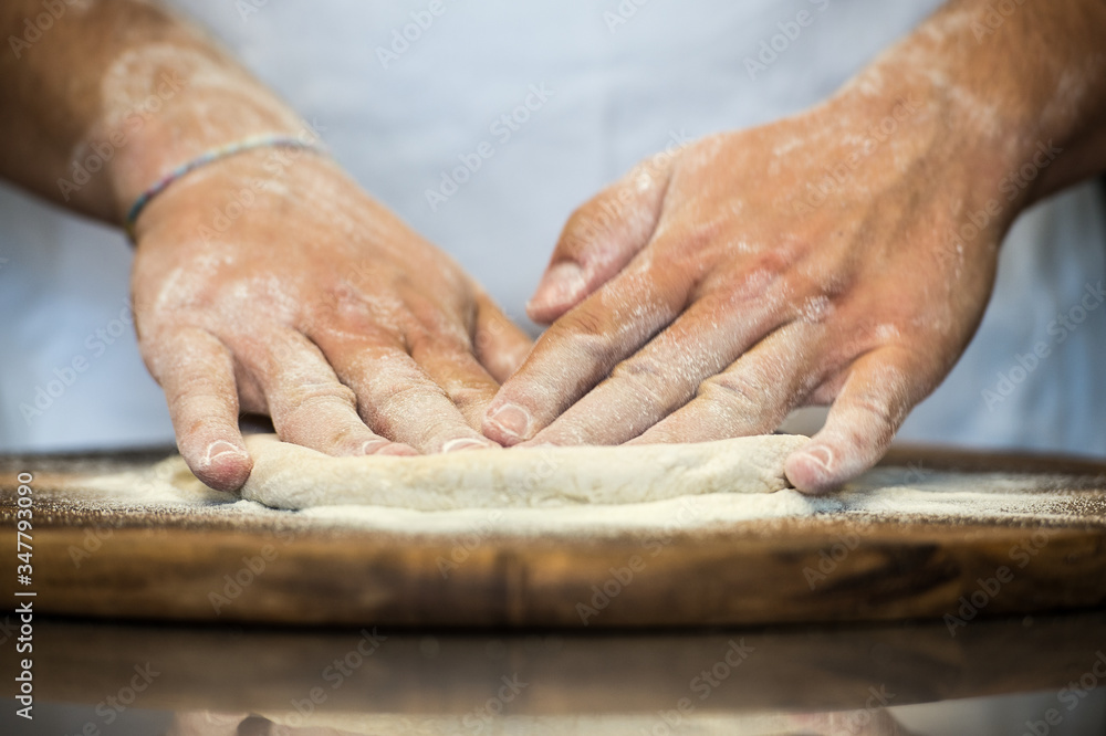 pizza maker preparing a pizza margherita  homemade with yeast flour and water.