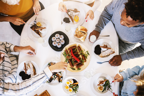 Photography Top view of five multicultural friends sitting at dinning table and having healthy lunch