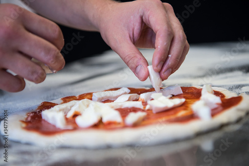 pizza Margherita. detail of the hands of a pizza maker who works for the various stages of preparing a real Italian pizza homemade with yeast flour and water.