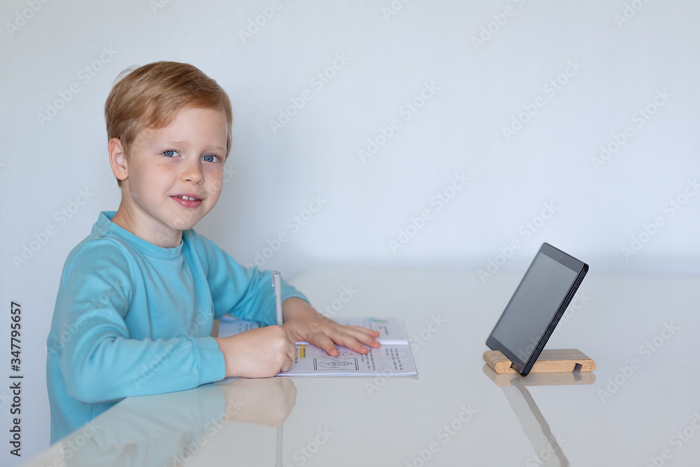 boy at table at home education with tablet computer boy at table at home education with tablet computer