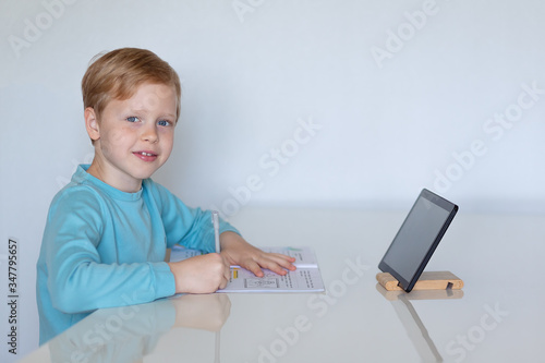 boy at table at home education with tablet computer
