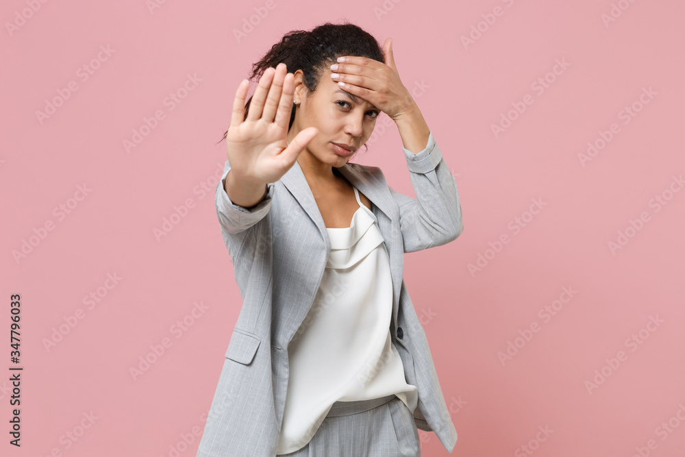 African american business woman in grey suit white shirt isolated on pink background. Achievement career wealth business concept. Mock up copy space. Showing stop gesture with palm, put hand on head. African american business woman in grey suit white shirt isolated on pink background. Achievement career wealth business concept. Mock up copy space. Showing stop gesture with palm, put hand on head.