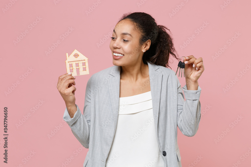 Smiling young african american business woman in grey suit white shirt posing isolated on pink background. Achievement career wealth business concept. Mock up copy space. Hold house and bunch of keys. Smiling young african american business woman in grey suit white shirt posing isolated on pink background. Achievement career wealth business concept. Mock up copy space. Hold house and bunch of keys.