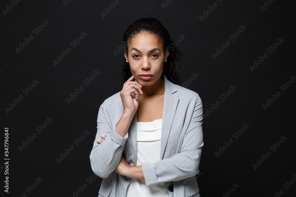 Confident young african american business woman in grey suit, white shirt posing isolated on black background. Achievement career wealth business concept. Mock up copy space. Put hand prop up on chin. Confident young african american business woman in grey suit, white shirt posing isolated on black background. Achievement career wealth business concept. Mock up copy space. Put hand prop up on chin.