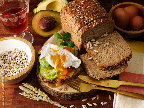 homemade avocado and egg bread sandwich with ingredients and wine cup in wood table background