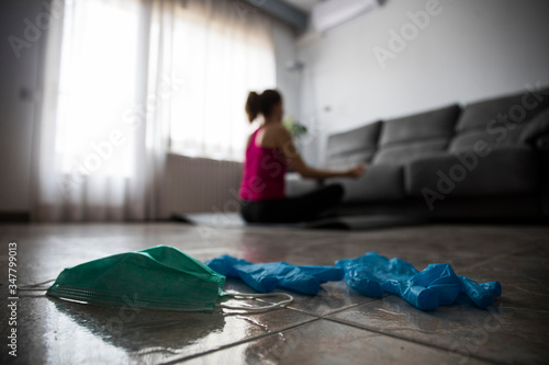 Girl doing yoga at home after breaking free from the protective mask and gloves from coronavirus, covid-19 photo