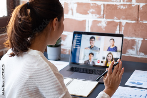 Young Asian businesswoman work at home and virtual video conference meeting with colleagues business people, online working, video call due to social distancing at home office photo