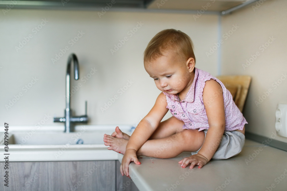 Funny baby Toddler sitting on a table in the kitchen Funny baby Toddler sitting on a table in the kitchen