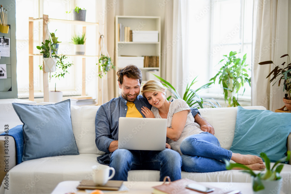 Happy couple in love sitting indoors at home, using laptop. Happy couple in love sitting indoors at home, using laptop.