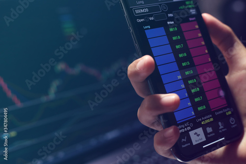 The Stock Exchange, Streaming Trade Screen, The stock screen Show the stock price rise, Trader hold the phone in hand.